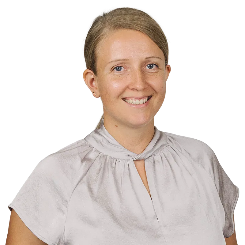 Porträt einer lächelnden Frau mit blonden Haaren und einem hellen Oberteil.